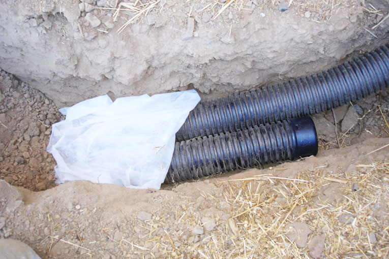 French drains need filter fabrics placed on top of the pipes